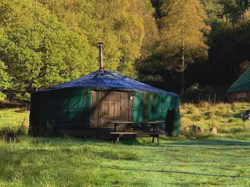 A green yurt with a chimney for the log burner.