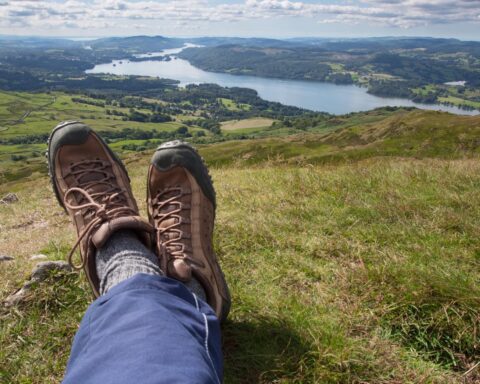 Relaxing and taking in the stunning view from the summit of Wansfell Pike looking south towards Lake Windemere in the Lake district, Northern England