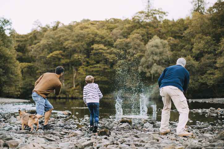 Family skimming stones on a lake - Free things to do in Cumbria with kids